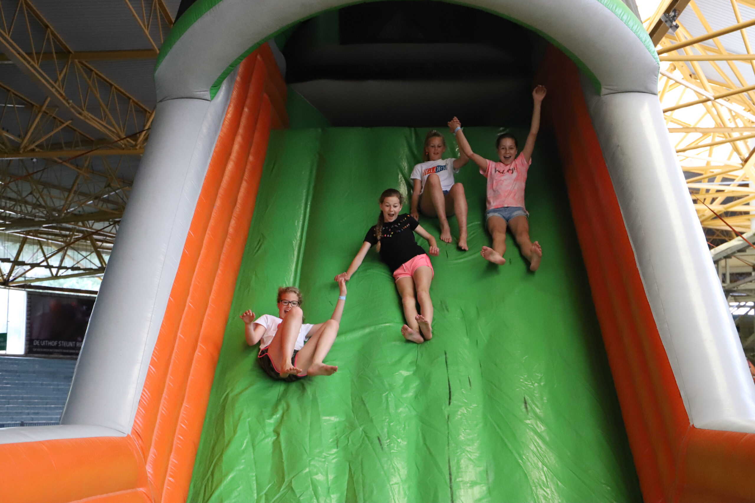 4 spelende kinderen die van een luchtkussen glijden